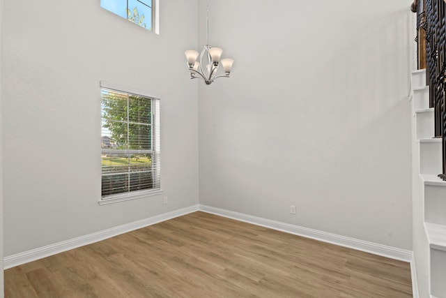 unfurnished room featuring a chandelier, plenty of natural light, and wood finished floors