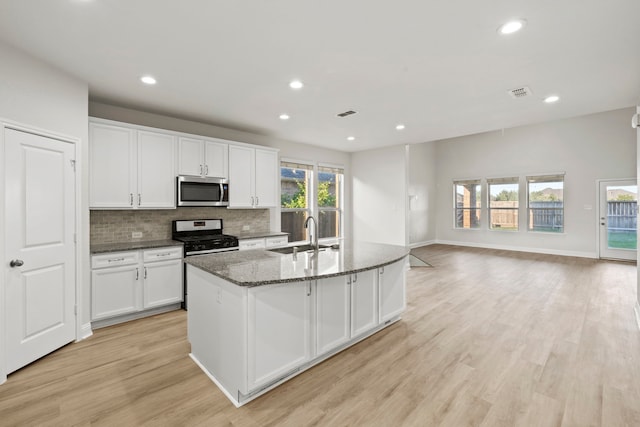 kitchen with a sink, stainless steel appliances, recessed lighting, white cabinets, and decorative backsplash