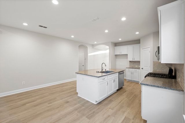 kitchen with a sink, arched walkways, appliances with stainless steel finishes, recessed lighting, and tasteful backsplash