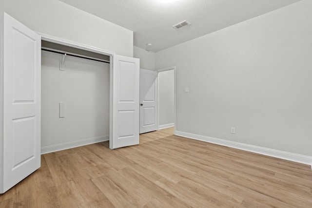 unfurnished bedroom featuring light wood finished floors, baseboards, and a closet
