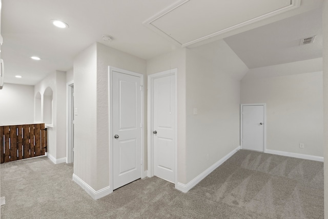hallway featuring carpet floors, attic access, baseboards, recessed lighting, and arched walkways