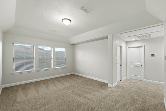 carpeted spare room featuring baseboards and attic access