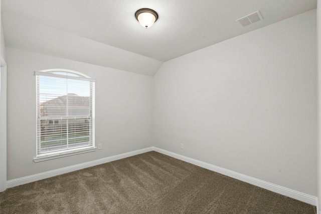 unfurnished room with dark colored carpet, baseboards, and lofted ceiling