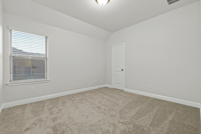 unfurnished room featuring carpet, vaulted ceiling, and baseboards