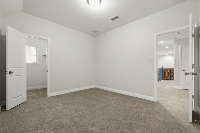 unfurnished bedroom featuring carpet flooring, a walk in closet, and baseboards