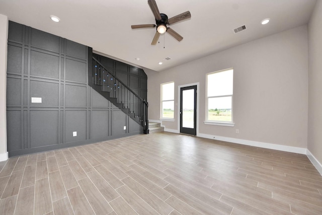11141 Rd 5503, Cleveland, TX 77327 - unfurnished living room with a decorative wall, stairway, a ceiling fan, baseboards, and light wood-type flooring