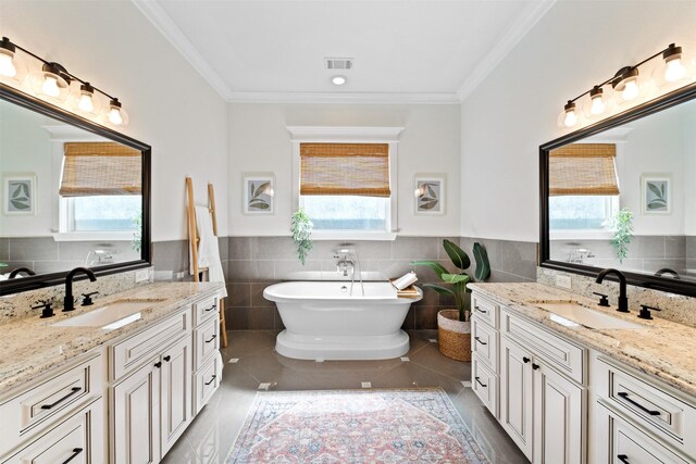 436 W 26th St, Houston, TX 77008 - full bath featuring tile walls, tile patterned floors, a freestanding tub, two vanities, and a wainscoted wall