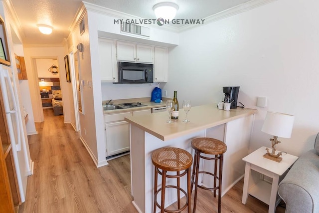 6300 Seawall Blvd Unit 9228, Galveston, TX 77551 - kitchen with black microwave, a breakfast bar area, light wood-style flooring, white cabinets, and crown molding
