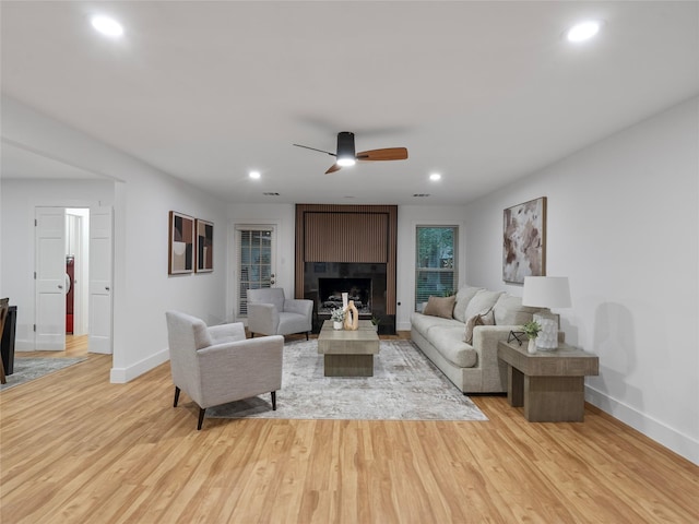 living room with baseboards, light wood-style floors, a ceiling fan, recessed lighting, and a large fireplace