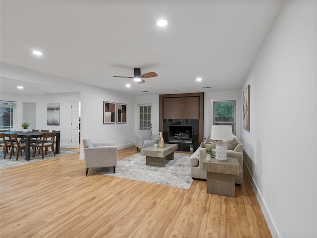 living room with a fireplace, baseboards, light wood-style floors, recessed lighting, and a ceiling fan