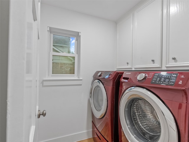 clothes washing area featuring washing machine and dryer, cabinet space, and baseboards