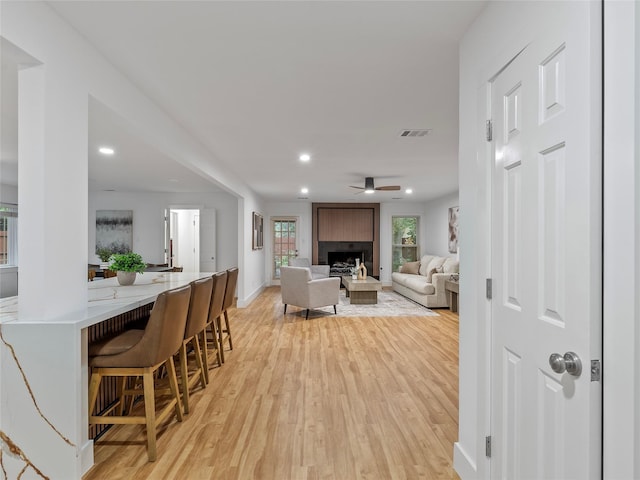 living room with light wood-style floors, a fireplace, ceiling fan, baseboards, and recessed lighting
