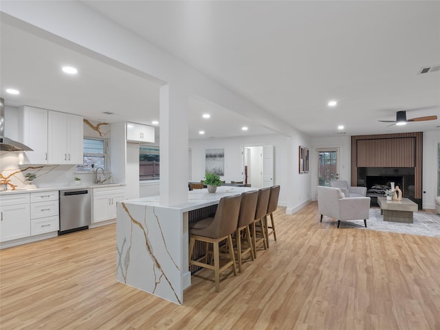 kitchen featuring dishwasher, light wood-style flooring, a large fireplace, white cabinets, and recessed lighting