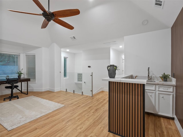 bar with a ceiling fan, light wood-type flooring, a sink, high vaulted ceiling, and baseboards