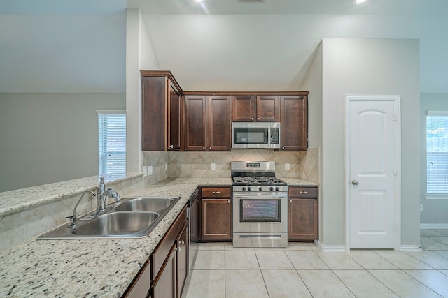 16702 Peralta Bay Cir, Crosby, TX 77532 - kitchen featuring stainless steel appliances, a sink, light tile patterned floors, dark brown cabinetry, and decorative backsplash
