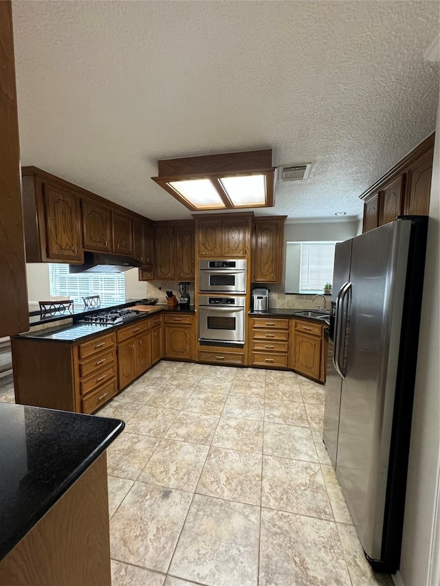 20706 Northcreek Ln, Houston, TX 77073 - kitchen with stainless steel appliances, dark countertops, a textured ceiling, a sink, and under cabinet range hood