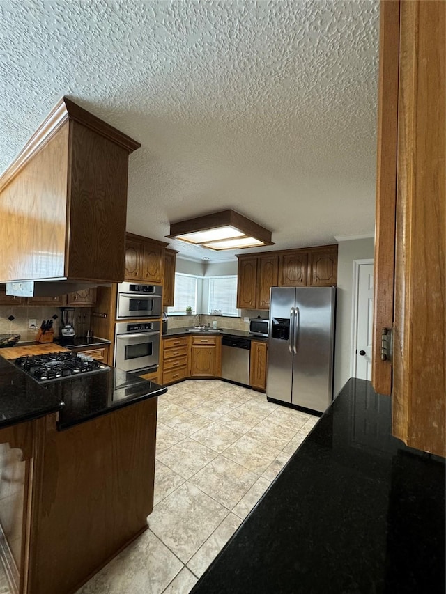 20706 Northcreek Ln, Houston, TX 77073 - kitchen featuring stainless steel appliances, a peninsula, a textured ceiling, light tile patterned floors, and dark countertops
