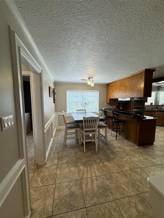 20706 Northcreek Ln, Houston, TX 77073 - dining room with crown molding, a wainscoted wall, a textured ceiling, and a decorative wall