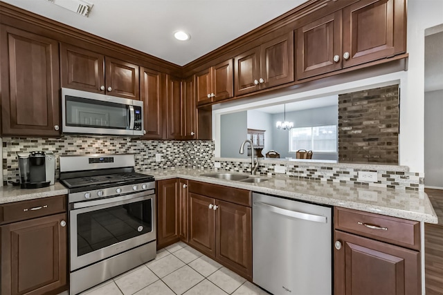 kitchen featuring stainless steel appliances, a sink, tasteful backsplash, a chandelier, and recessed lighting