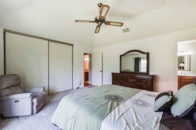 carpeted bedroom featuring a closet, connected bathroom, a sink, vaulted ceiling, and a ceiling fan