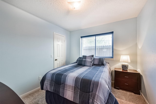 bedroom with carpet, baseboards, and a textured ceiling