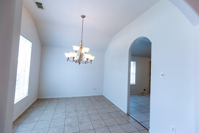 unfurnished room with healthy amount of natural light, a chandelier, vaulted ceiling, arched walkways, and light tile patterned floors