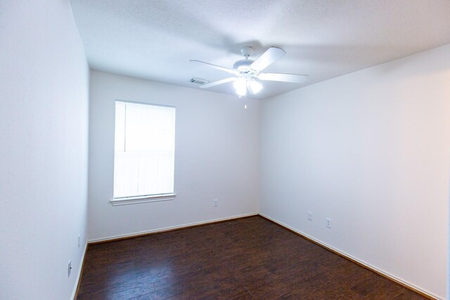 unfurnished room featuring dark wood-type flooring, ceiling fan, and baseboards