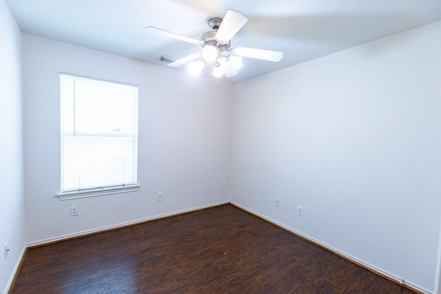 spare room with dark wood-type flooring, ceiling fan, and baseboards