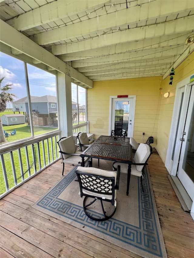 sunroom / solarium featuring healthy amount of natural light, beam ceiling, outdoor dining space, and a residential view