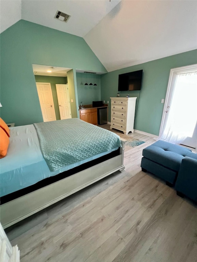 bedroom with lofted ceiling, wood finished floors, baseboards, and a sink