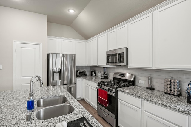 3306 Old Ironwood Dr, Spring, TX 77386 - kitchen featuring stainless steel appliances, a sink, lofted ceiling, white cabinets, and dark wood finished floors