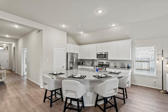 3306 Old Ironwood Dr, Spring, TX 77386 - kitchen with stainless steel appliances, light stone countertops, a breakfast bar area, light wood-style floors, and vaulted ceiling