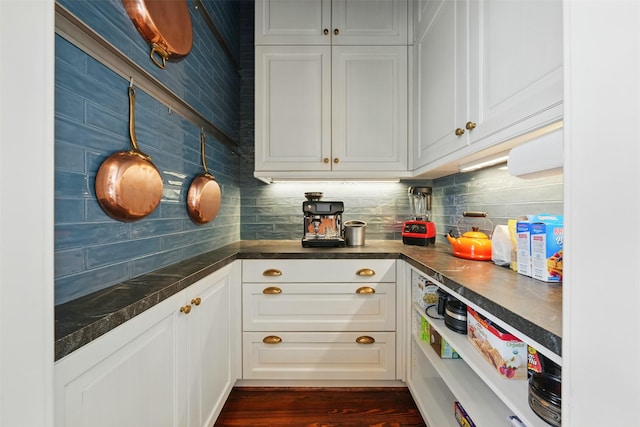 215 Bayland Ave, Houston, TX 77009 - kitchen featuring dark countertops, backsplash, white cabinets, and dark wood finished floors