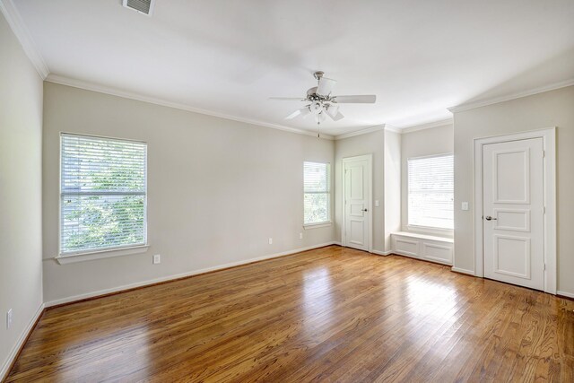 spare room with a ceiling fan, wood finished floors, baseboards, and ornamental molding