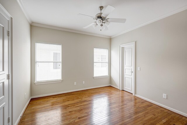 empty room featuring plenty of natural light, wood-type flooring, a ceiling fan, and ornamental molding