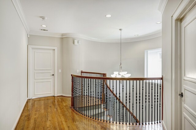 corridor featuring an upstairs landing, a chandelier, wood finished floors, crown molding, and recessed lighting
