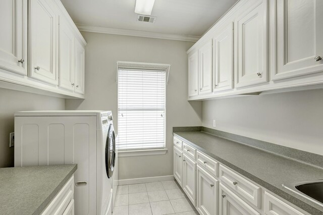 laundry area featuring washer / clothes dryer, cabinet space, crown molding, baseboards, and light tile patterned floors