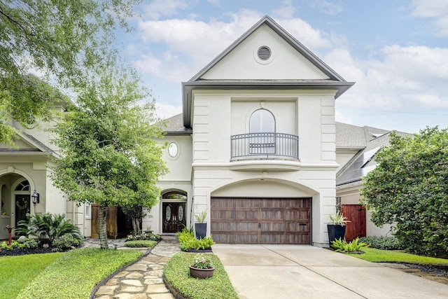 view of front facade with a balcony, a garage, stucco siding, and concrete driveway