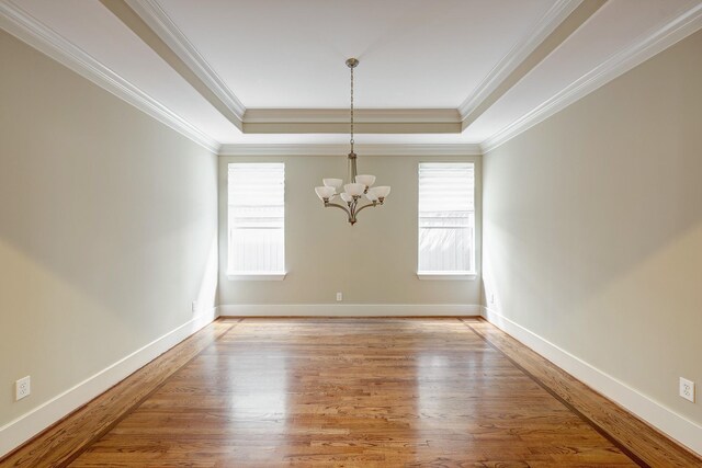 empty room with a chandelier, plenty of natural light, light wood-style floors, and crown molding