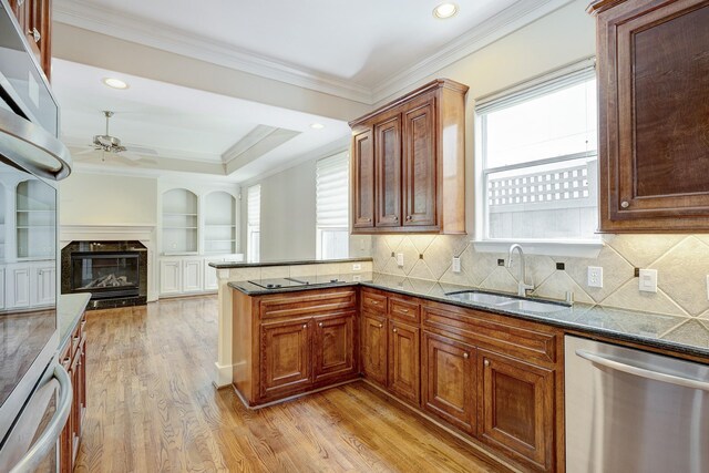 kitchen featuring stainless steel dishwasher, a sink, light wood-style flooring, healthy amount of natural light, and crown molding