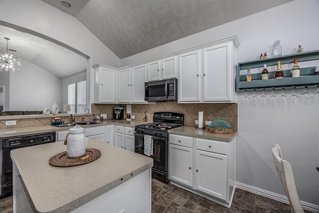 kitchen featuring black appliances, vaulted ceiling, a sink, decorative backsplash, and a chandelier