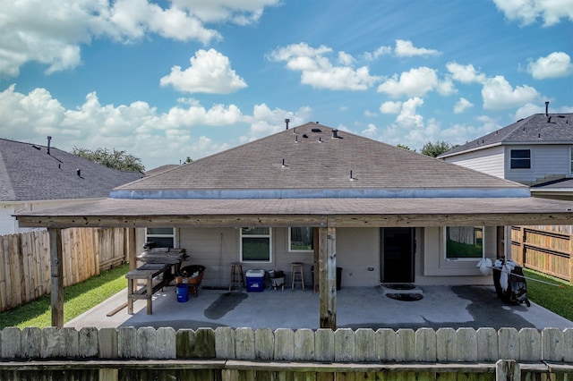 rear view of house with a patio, a fenced backyard, and roof with shingles