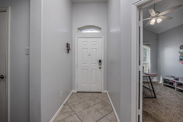 entryway with a ceiling fan, light tile patterned floors, baseboards, and lofted ceiling