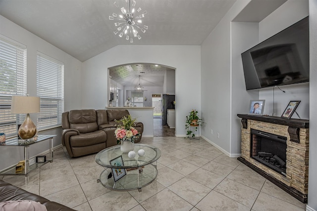 living area with a chandelier, lofted ceiling, arched walkways, baseboards, and a stone fireplace