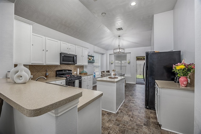 kitchen with black appliances, a center island, stone finish floors, white cabinetry, and backsplash