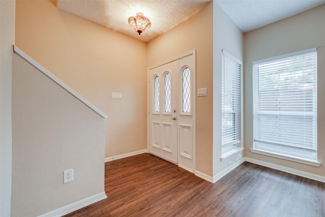 foyer featuring wood finished floors, baseboards, and a textured ceiling