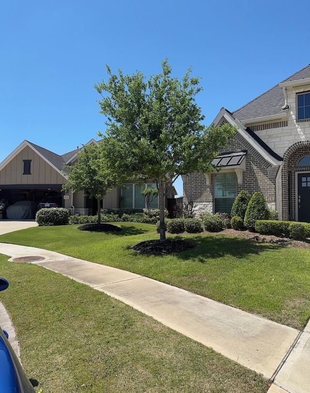 7010 Goldstrum Way, Katy, TX 77493 - view of front facade featuring a front lawn, board and batten siding, brick siding, a shingled roof, and stone siding