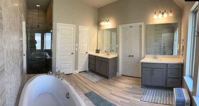 7010 Goldstrum Way, Katy, TX 77493 - full bath featuring two vanities, a garden tub, tiled shower, wood finished floors, and baseboards