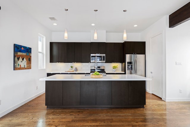 910 W 19th St Unit A, Houston, TX 77008 - kitchen featuring appliances with stainless steel finishes, light countertops, a large island with sink, baseboards, and recessed lighting