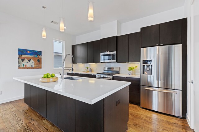 910 W 19th St Unit A, Houston, TX 77008 - kitchen featuring appliances with stainless steel finishes, a sink, light countertops, light wood-type flooring, and a center island with sink